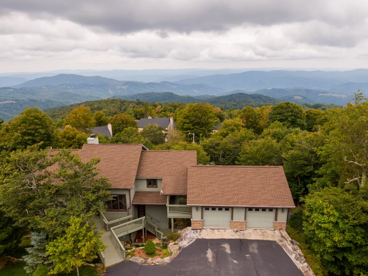 The hero image showcases a spacious single-family home perched amidst lush trees with a dramatic mountain backdrop. The scene exudes tranquility, hinting at breathtaking sunrise views and starlit nights. A generous porch invites guests to relax and soak in the surrounding natural beauty, while the secluded setting promises privacy and peace.