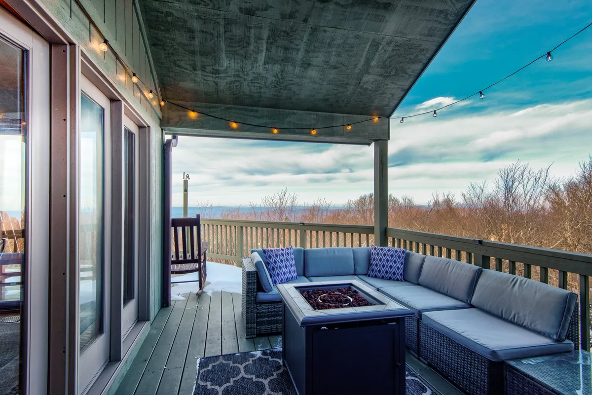 An inviting outdoor seating area with a fire pit and string lights overlooks sweeping landscape views. The setup is ideal for gatherings, stargazing, and unwinding after a day of exploration, surrounded by nature.