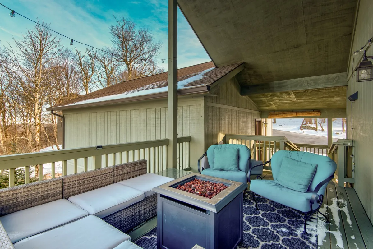 An inviting outdoor space featuring a cozy fire pit surrounded by comfortable seating, set amid trees. The scene suggests social gatherings, marshmallow roasting, and enjoying the winter air after a day on the slopes.
