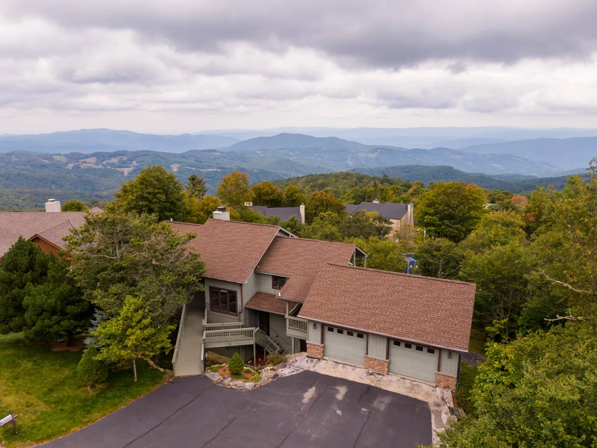 This image captures the house facade framed by lush trees and a mountainous landscape, creating an inviting scene for outdoor relaxation and family gatherings. The tranquil setting hints at the nearby trails and natural beauty waiting to be explored.