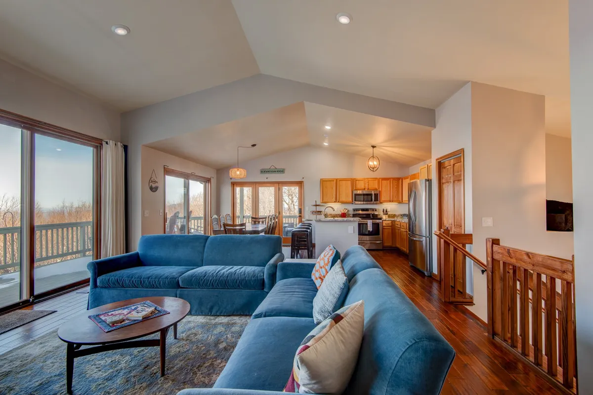 An open-plan living area featuring a blue sofa, wooden dining table, and kitchen area. The space feels inviting and familial—ideal after a day exploring with your dog.